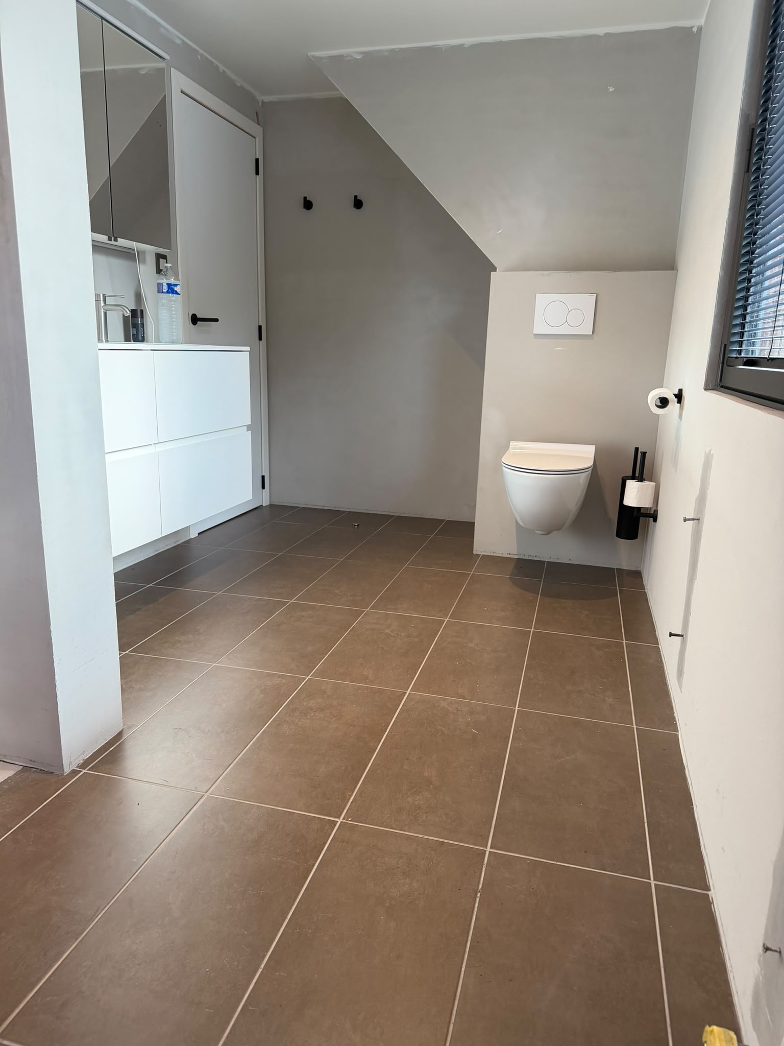 Badkamer met wastafelmeubel voor de werken - betegelde vloer