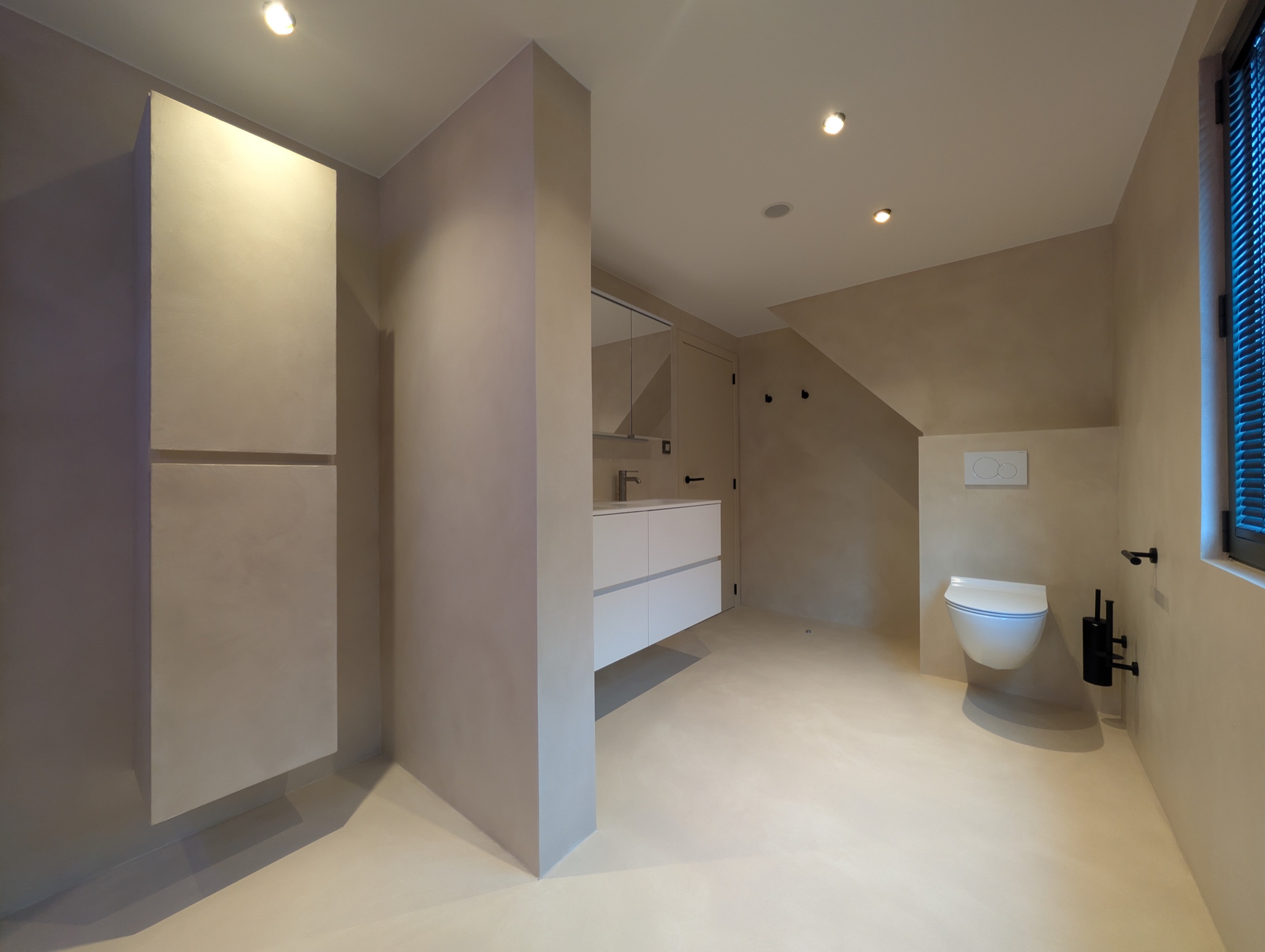 Microcement badkamer met wastafelmeubel en hoge kastenwand